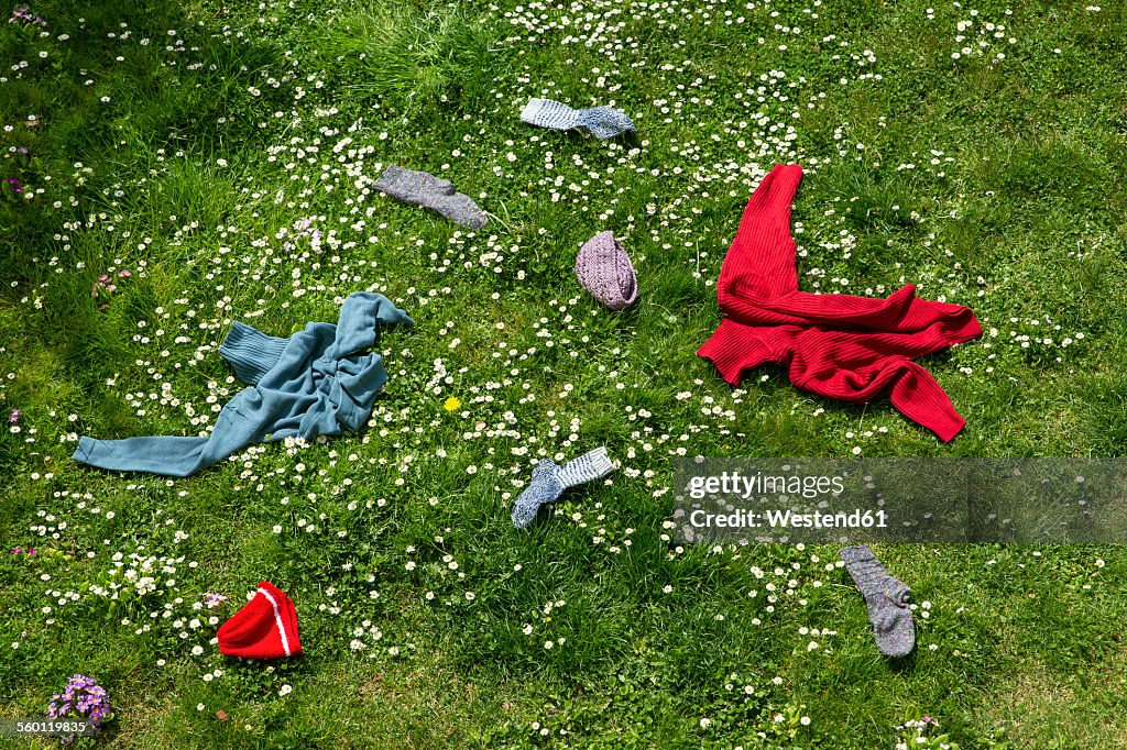 Winter clothes lying scattered in spring meadow