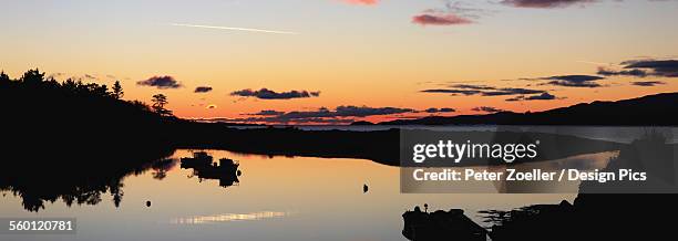 golden sunrise on the horizon with a silhouette of the shoreline reflected in a tranquil lake, rosdohan pier - sneem stock pictures, royalty-free photos & images