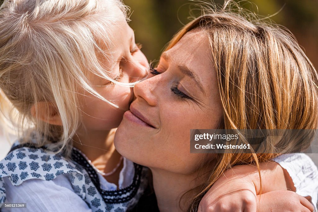 Girl hugging and kissing smiling mother