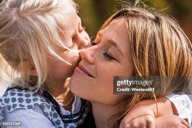 girl hugging and kissing smiling mother - mother and daughter kiss happy stock-fotos und bilder