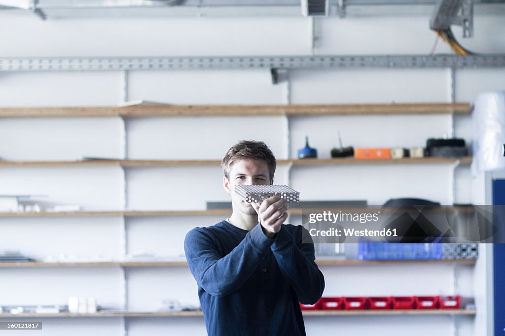 Technician in workshop examining piece of metal