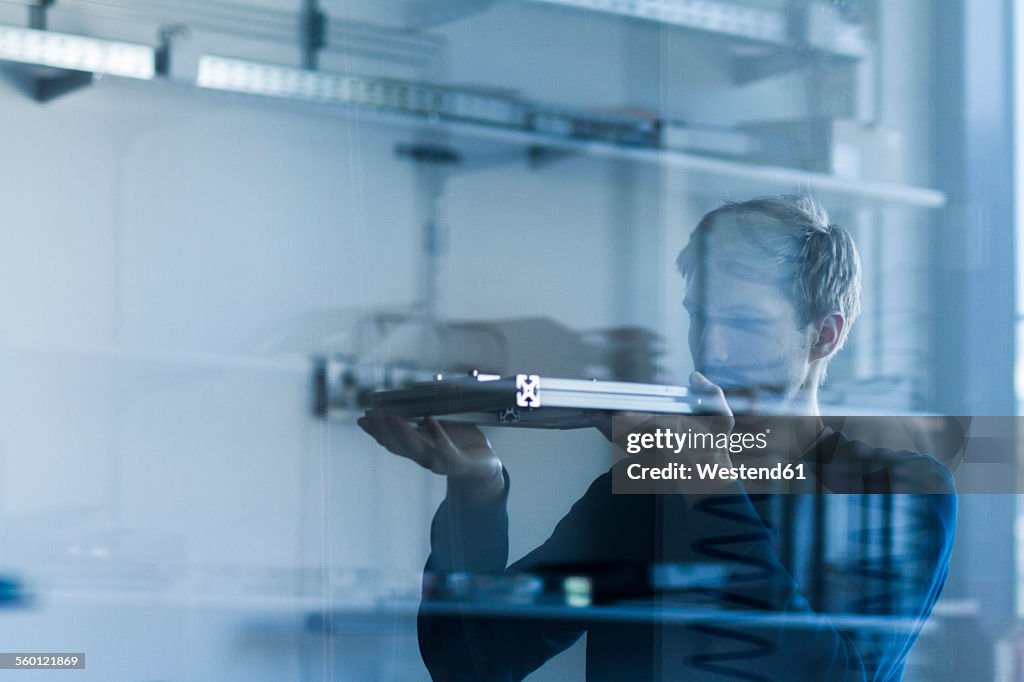 Technician in workshop examining piece of metal