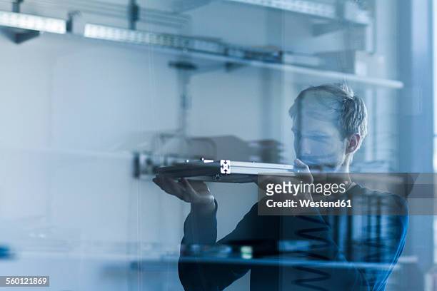 technician in workshop examining piece of metal - glass material 個照片及圖片檔