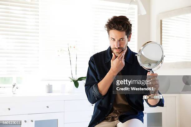man sitting in bathroom looking at mirror - vanity stock pictures, royalty-free photos & images
