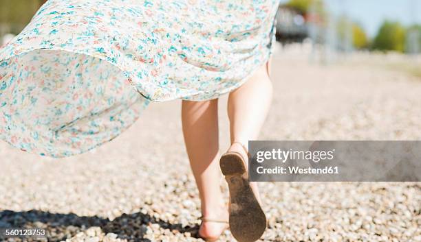 woman walking on shingle beach - vestido de verão imagens e fotografias de stock