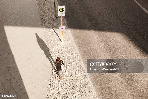 young woman walking to bus stop - bushaltestelle stock-fotos und bilder