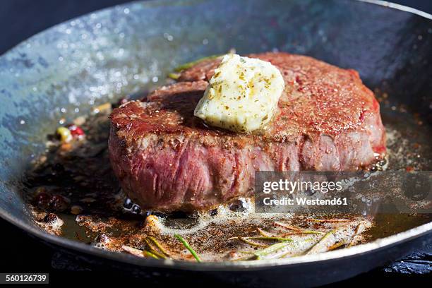 fried fillet of beef with herb butter, peppercorns and rosemary in a pan - biefstuk stockfoto's en -beelden