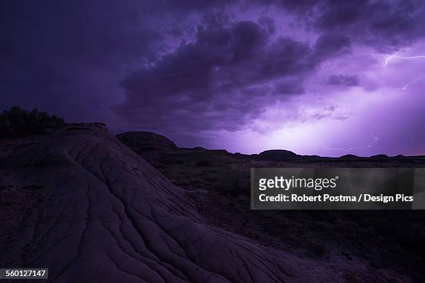 lightning illuminates the skies as a storm front moves over dinosaur provincial park - dinosaur provincial park foto e immagini stock