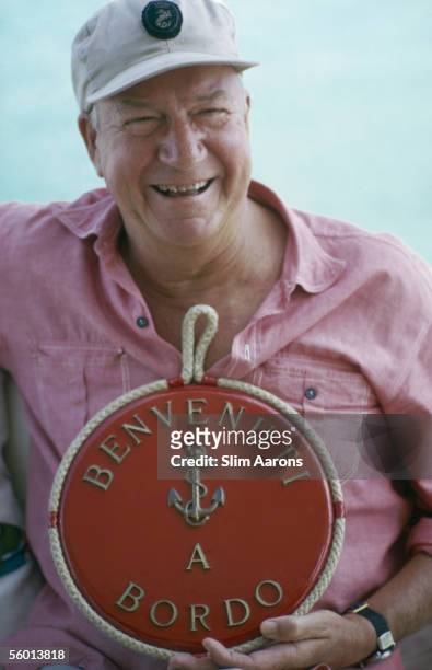 Yachtsman and writer Carleton Mitchell welcomes guests on board his yacht, Sans Terre, at Lyford Cay, New Providence Island, April 1974.