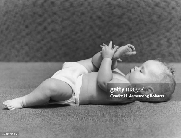 Baby contemplates the sole of its foot, circa 1950.