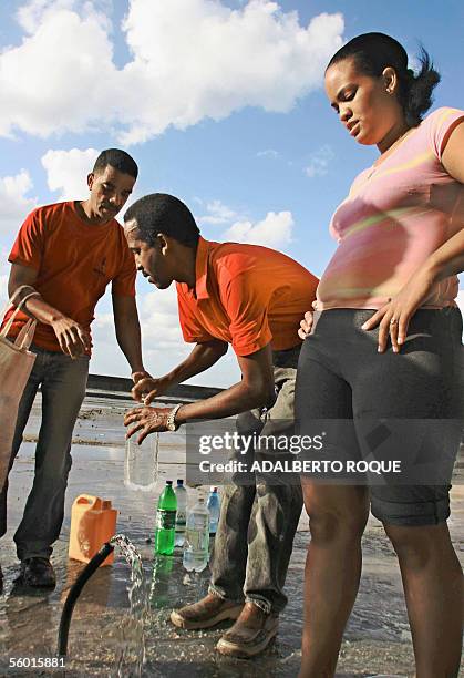 Habitantes del barrio La Habana Vieja embotellan agua potable el 26 de octubre del 2005, tras pasar varios dias sin fluido electrico y sin agua...