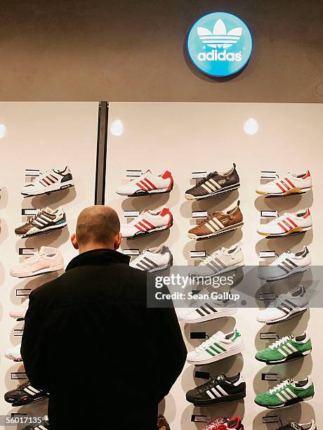 Man looks at Adidas shoes on display during the opening of the new Adidas Performance Store October 26, 2005 in Berlin, Germany. Adidas-Salomon AG is...