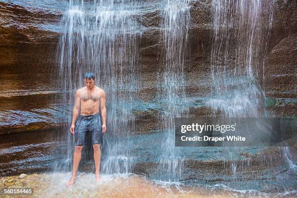 man bathes in waterfall - badehose stock-fotos und bilder