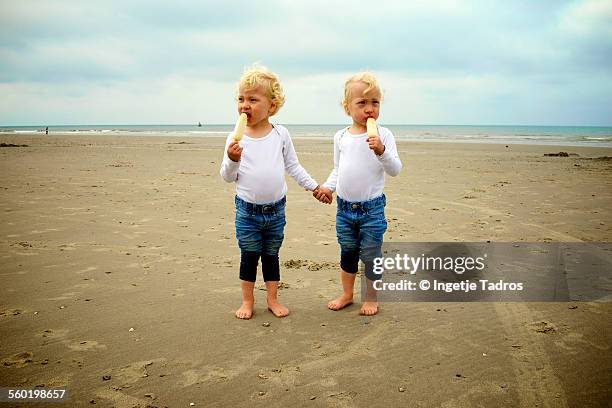 twins eating icecream on the beach - vlieland stock pictures, royalty-free photos & images
