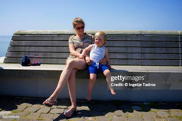 young mother sitting on wooden beanch with her son - vlieland stock pictures, royalty-free photos & images