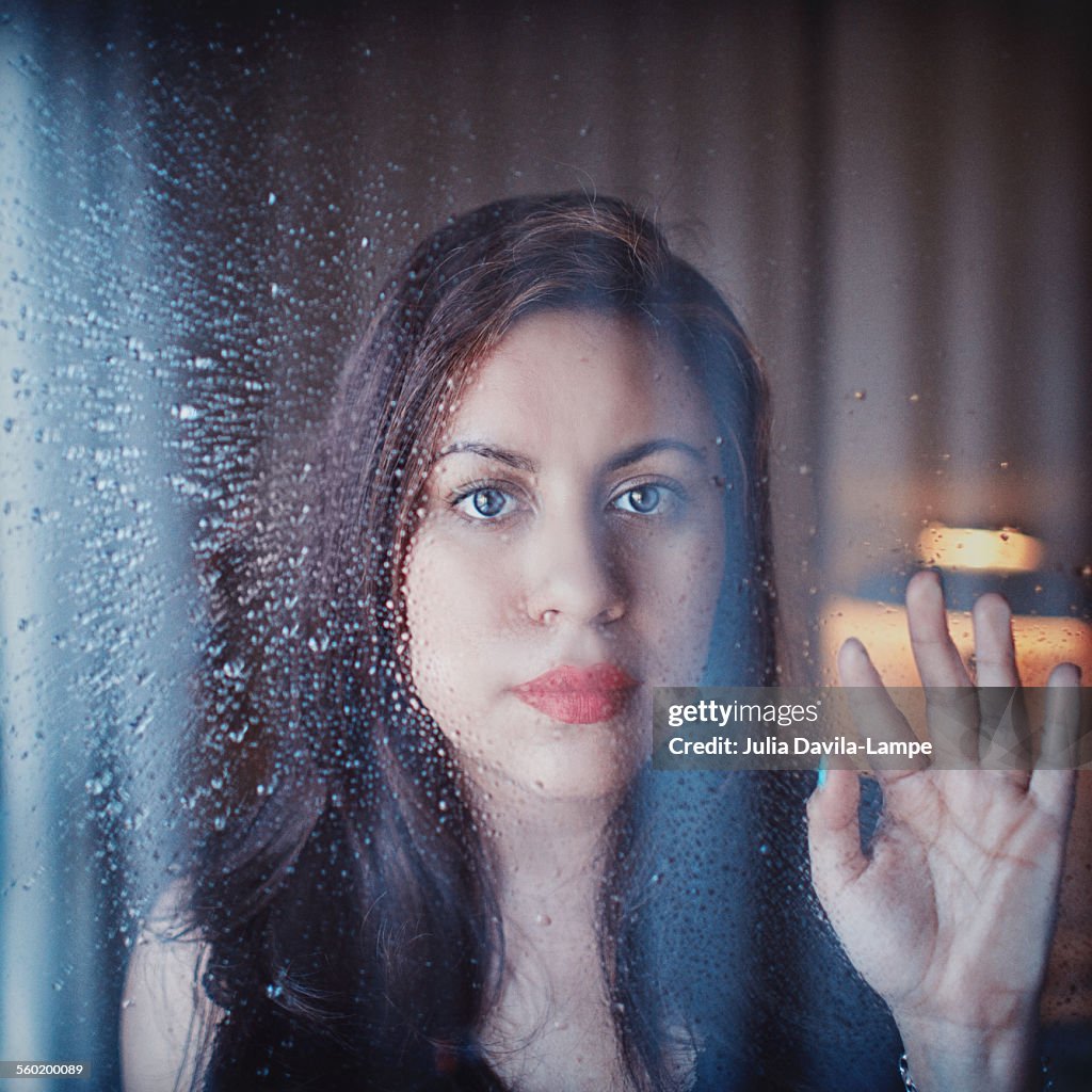 Woman behind rainy window