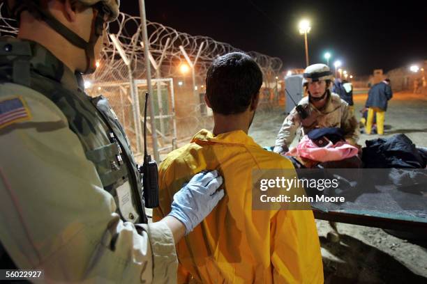 Army military policemen issue cold weather clothing and blankets to suspected insurgents while processing new detainees at the Abu Ghraib Prison...