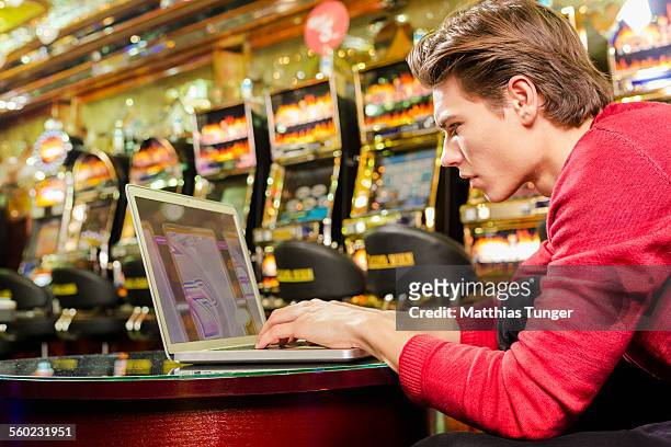 young man playing poker on his laptop - poker card game stockfoto's en -beelden