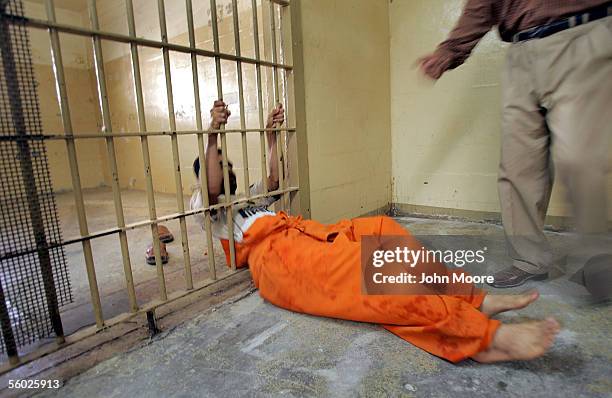 An Iraqi prisoner at Abu Ghraib slides through a hole cut in the bars of a cell in the criminal section of the prison October 28, 2005 on the...