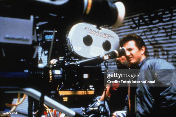 American actor Sean Penn looks through the lens of the camera on the set of his film 'The Crossing Guard,' 1995. 'The Crossing Guard' marks the...