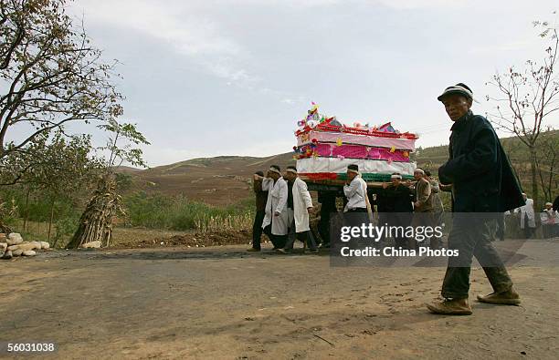 Family members carry the coffin of the dead during the funeral of a senior citizen in Jiaodai Township on October 27, 2005 in Lantian County of...