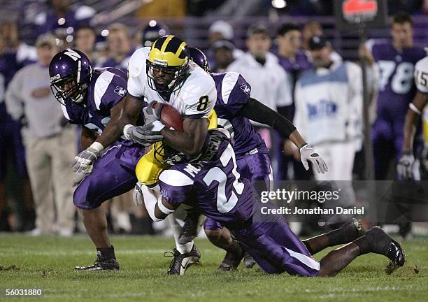 Wide receiver Jason Avant of the Michigan Wolverines is brought down by Reggie McPherson of the Northwestern Wildcats as Nick Roach and Marquice Cole...