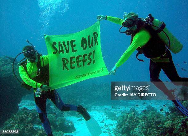 Crew members from the Greenpeace flagship Rainbow Warrior display a banner saying "Save our reefs!" at the world famous Tubbataha Reef National...