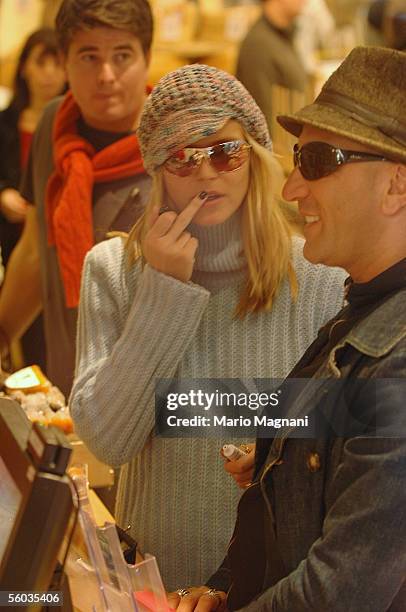 Model Heidi Klum makes an obscene gesture as she applies lip balm inside a gourmet grocery October 30, 2005 in New York City.