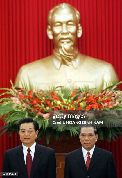 Visiting Chinese President and communist party Chairman Hu Jintao and Vietnamese communist party secretary general Nong Duc Manh stand under a statue...