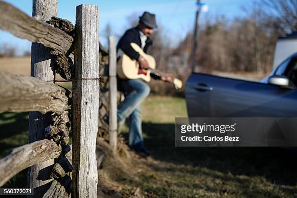 man playing guitar on the fence - sturbridge stock pictures, royalty-free photos & images