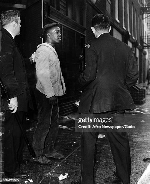Baltimore Police officers with billy clubs and shotgun arresting a young African-American protester during the aftermath of a riot, at Franklin...