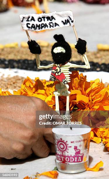 Una mujer acomoda una esqueleto con un pasamontanas, en refencia a los miembros del EZLN , junto a flores de cempazuchitl en un altar de muertos...