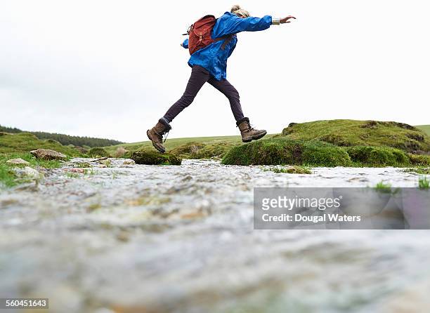 hiker stepping across stream in countryside - hiking boot stock pictures, royalty-free photos & images