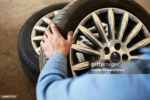 garage mechanic examining car tyre - rire stock-fotos und bilder