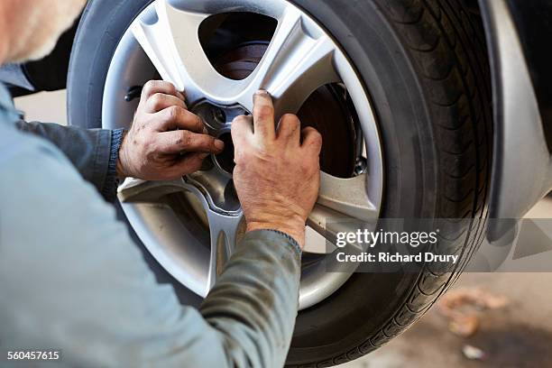 garage mechanic fitting car wheel - only mature men fotografías e imágenes de stock