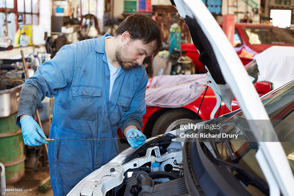 Car mechanic checking engine oil