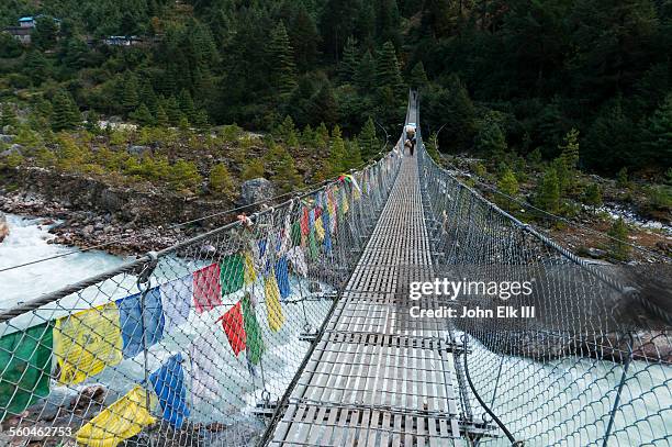 porter crossing dudh kosi gorge suspension bridge - gokyo valley stock pictures, royalty-free photos & images