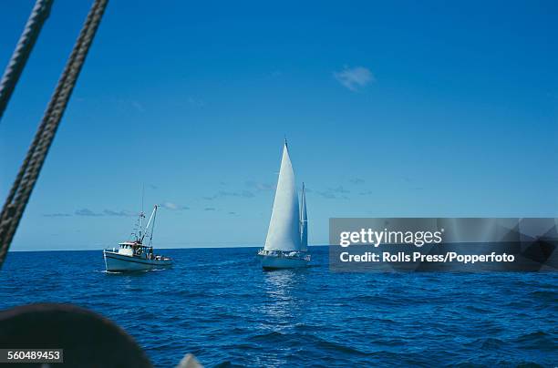 View of the yawl Gipsy Moth IV, sailed by Francis Chichester, accompanied by a trawler off the coast of New South Wales, Australia on 7th December...