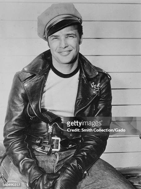 Actor Marlon Brando wearing a leather jacket, jeans, and a conductor hat, 1954.