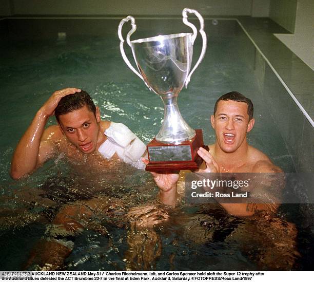 Charles Riechelmann, left, and Carlos Spencer hold aloft the Super 12 trophy after the Auckland Blues defeated the ACT Brumbies 237 in the final at...