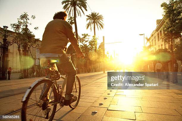 cyclist riding into sunset in sevilla, spain - palm sunday stockfoto's en -beelden