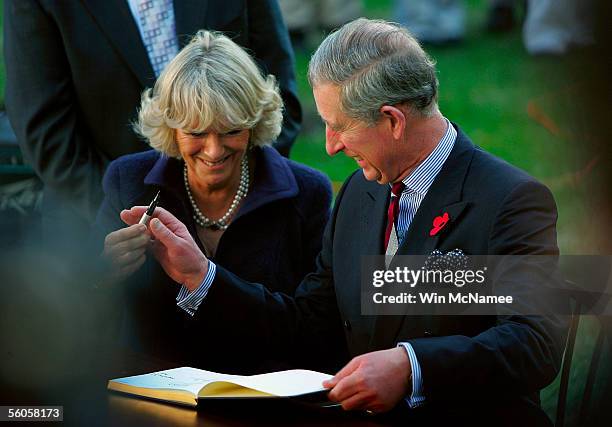 Britain's Prince Charles laughs with his wife Camilla, Duchess of Cornwall, before signing a guest book following a tour at the SEED Public Charter...