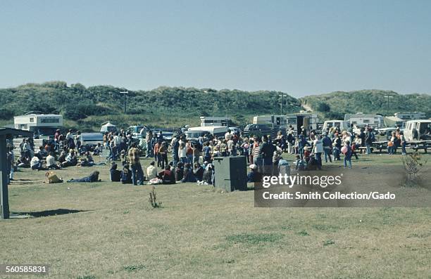 Large group of people with camper vans and recreational vehicles, in a field, Oregon, 1966.