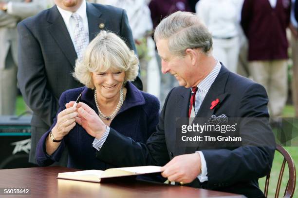 Prince Charles, Prince of Wales and Camilla, Duchess of Cornwall giggle as she is reluctant to return his pen as they sign the visitors' book at SEED...