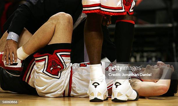 Trainer Fred Tedeschi of the Chicago Bulls comes to the assistance of guard Kirk Hinrich after Hinrich injured his ankle during a game against the...