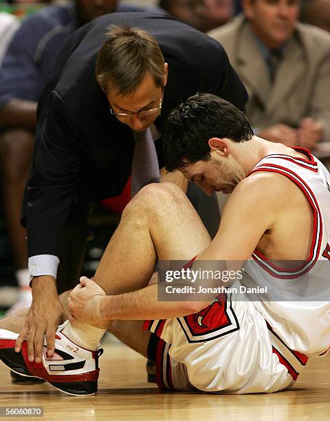 Trainer Fred Tedeschi of the Chicago Bulls comes to the assistance of guard Kirk Hinrich after Hinrich injured his ankle during a game against the...