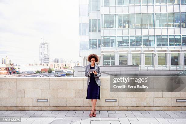 mixed-race businesswoman using tablet in city - modern maturity center foto e immagini stock