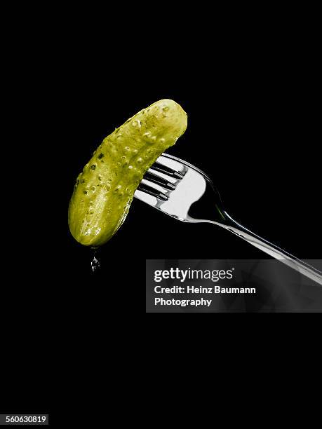 dripping pickle speared on a fork on black backgro - heinz baumann photography stock pictures, royalty-free photos & images