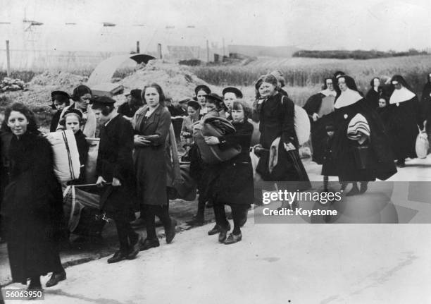 Belgian schoolgirls and nuns, displaced from their convent by German attacks on the Low Countries, arrive at a French refugee centre during World War...