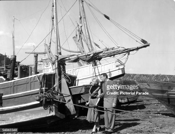 Recently married American actress Marilyn Monroe and her husband, American baseball player Joe DiMaggio look at beached sailboats while on their...